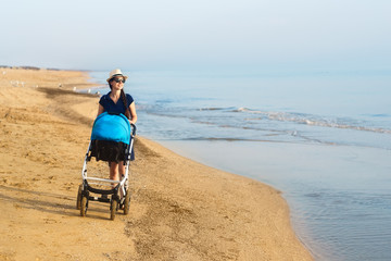 mother walking with stroller on the sea beach