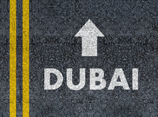 DUBAI with arrow written with paint on road asphalt