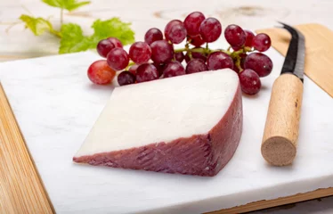 Gartenposter Traditional Spanish cheese, Murcian wine cheese from goat milk with rind washed in red wine, served with fresh ripe grapes © barmalini