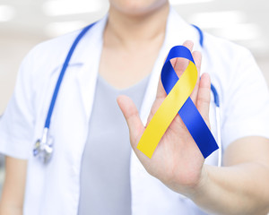 Doctor with blue and yellow ribbon awareness in hand for Down Syndrome ,Thoracic Outlet Syndrome - (TOS),World down syndrome day WDSD 