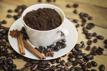 Cup full of ground coffee with coffee beans