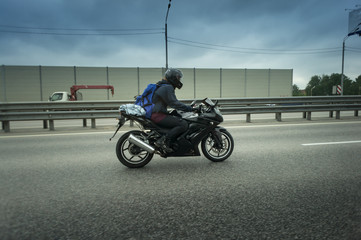 young man riding sport motorcycle on the highway with metal safety barrier or rail