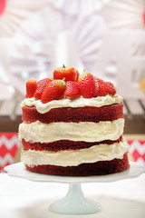Red cake with strawberries and cream on white plate