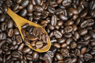 Fresh coffee beans and wooden spoon on table
