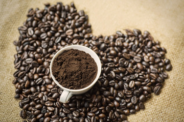 Ground coffee cup with coffee beans on table