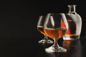 Two glasses of brandy or cognac and bottle on black