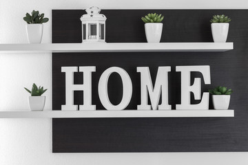 Home letters decor on white shelf with dark wood background on white wall