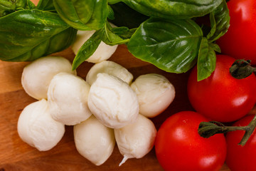 Mozzarella tomatoes and basil on a wooden rustic background