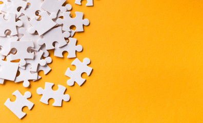 Pile of puzzles ob yellow background, copy space