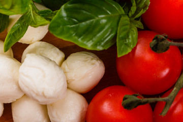 Mozzarella tomatoes and basil on a wooden rustic background