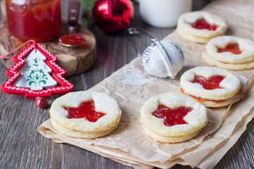 Homemade cutout jam filled cookies (Linzer cookies with strawberry jam) and bottle of milk on rustic background. Festive decoration. Traditional Austrian Christmas cookies.