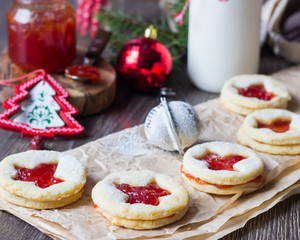 Homemade cutout jam filled cookies (Linzer cookies with strawberry jam) and bottle of milk on rustic background. Festive decoration. Traditional Austrian Christmas cookies.