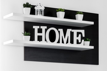 Home letters decor on white shelf with dark wood background on white wall