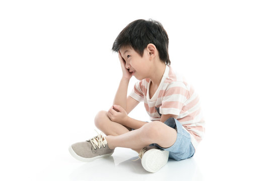 Close up of sad Asian boy sitting on white background isolated