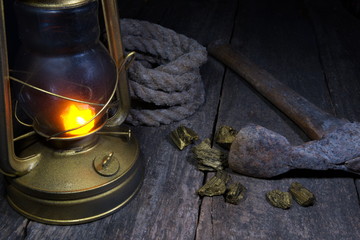 Fototapeta na wymiar Lantern, axe, gold mining and treasure hood concept.Wood background