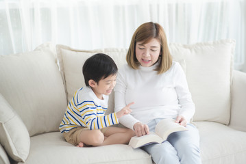Asian mother Sitting With Son Reading Story together