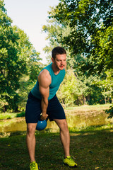 Man holding kettlebell while training his body in the park