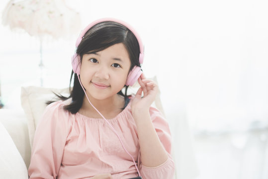 Beautiful Asian girl listening to music  sitting on a sofa in the living room at home