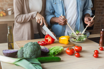 Black couple preparing vegetable salad in kitchen