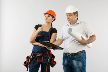 An architect man wearing a hard hat or helmet and co-worker builder woman reviewing blueprints