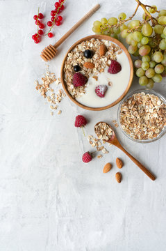 Bowl of muesli with natural yogurt on concrete background. Vertical food photo. Top view. Copy space. 