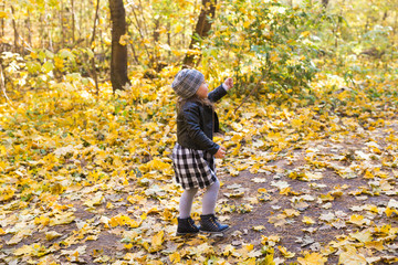 Fall, childhood, people concept - little happy girl walking in autumn park