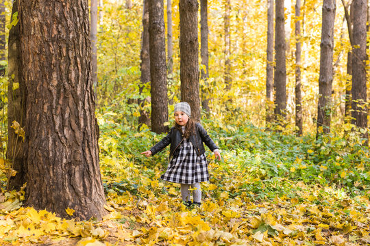 Fall, childhood and children concept - little happy girl in the autumn park