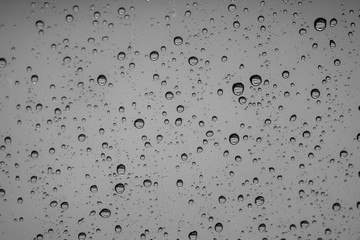 Rain drops on outside car mirror window glasses surface with cloudy background . Natural pattern of raindrops on cloudy background. Shallow depth of field.