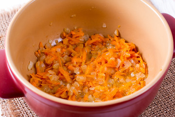 Sliced carrots in a saucepan on a wooden background