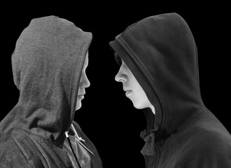 Two troubled teenage boys with black hoodie standing in front of each other in profile isolated on...