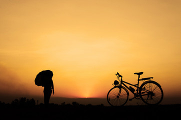Fototapeta premium Silhouette woman with bicycle, walking, sunset background