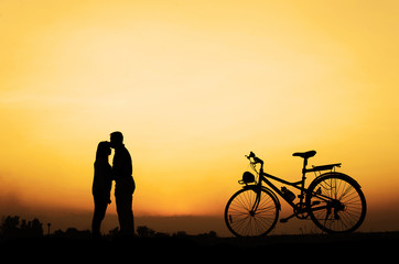 Fototapeta premium Silhouette of sweet couple in love happy time and bicycle in beautiful sunset