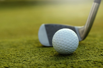The golf ball and golf club with the warm light of the evening