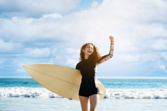 Girl holding surfboard running down to sea. Bright blue sea in the evening for surfing. During long weekend of summer Feel refreshed and relaxed. sunscreen help protect the skin against sun exposure.