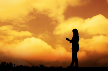 Silhouette woman on the phone with a sunset background