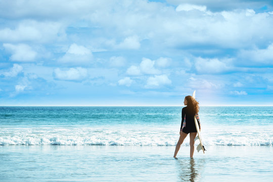 Girl holding surfboard Stand in to sea. Bright blue sea in the evening for surfing. During long weekend of summer Feel refreshed and relaxed. sunscreen help protect the skin against sun exposure.