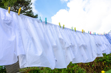 White shirts hanging outside on a washing line to dry.