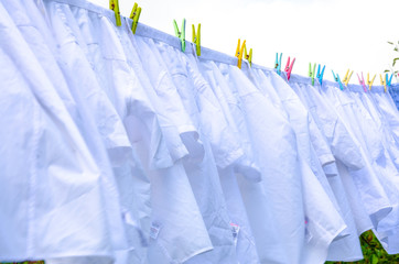 White shirts hanging outside on a washing line to dry.