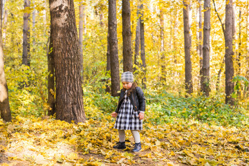 Childhood, fall, people concept - little girl walking in autumn leaves.
