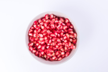 Pomegranate seeds in a bowl on a white