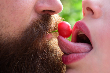 Sexy couple kissing with cherry. Young lovers. Couple in love. Erotic moments. Hot babe. Concept of sensual and intimate moment of lovers. Beautiful lady and guy in erotic pose. Oral sex concept