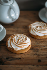 Tartlet with lemon cream and meringue on old rustic wooden background