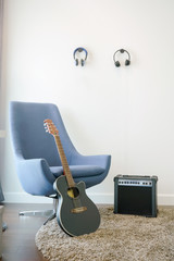 Music corner in the living room with retro style armchair, headphones and guitar