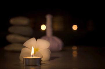 Spa concept: candle, Plumeria, stone with warm light in the dark
