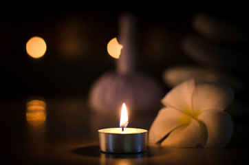 Obraz na płótnie Canvas Spa concept: candle, Plumeria, stone with warm light in the dark