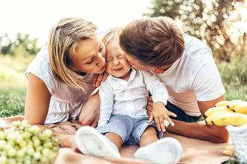 Young parents with little baby boy on picnic outdoor