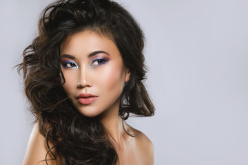 Jeune femme asiatique avec de beaux cheveux bouclés et maquillage