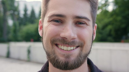 A happy smiling man with a beard in the city street. Close-up shot. Soft focus