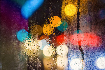 Rain drops on window with blurred glowing background