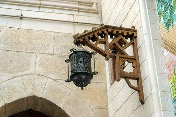 Old iron lantern with a cross hanging from a wooden frame on a stone wall of an old church of Coptic religion